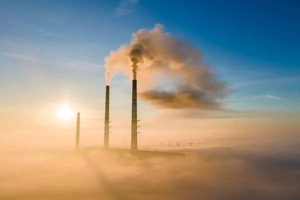 Повітряний вид на високі труби вугільної електростанції з чорним димом, що рухається вгору, забруднюючи атмосферу на заході сонця — стокове фото