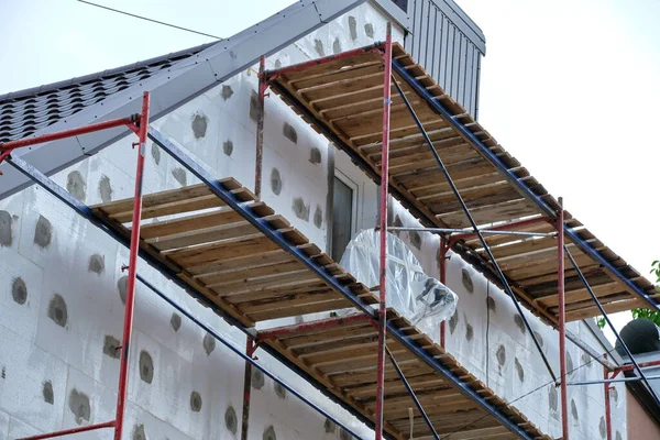 Fachada de construção em obras de renovação com estrutura de andaimes de construção. Isolamento de parede com folhas de isopor para casa eficiente em termos energéticos — Fotografia de Stock