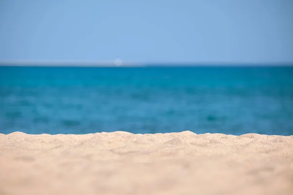 Close up de superfície de areia amarela limpa cobrindo praia à beira-mar com água do mar azul no fundo. Conceito de viagem e férias — Fotografia de Stock