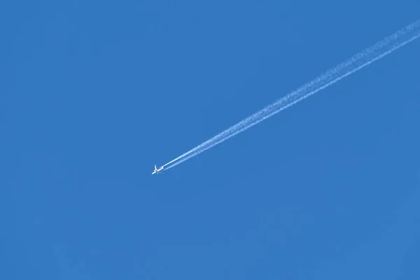 Avion à réaction de passagers éloigné volant à haute altitude sur ciel bleu clair laissant derrière lui des traces de fumée blanche. Concept de transport aérien — Photo