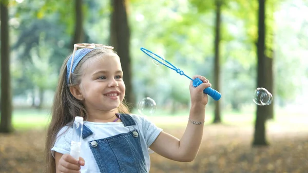 Yaz parkında sabun köpüğü üfleyen küçük mutlu kız çocuğu. — Stok fotoğraf