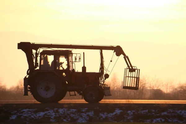 Мобильный подъемный крановый трактор, движущийся по междугородней дороге на закате — стоковое фото