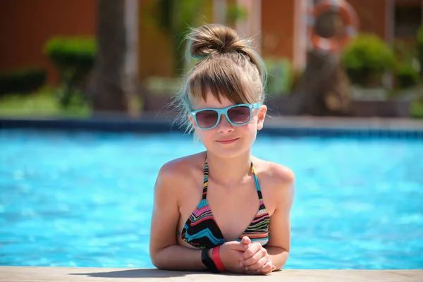 Retrato da menina criança feliz relaxando no lado da piscina no dia ensolarado de verão durante as férias tropicais — Fotografia de Stock