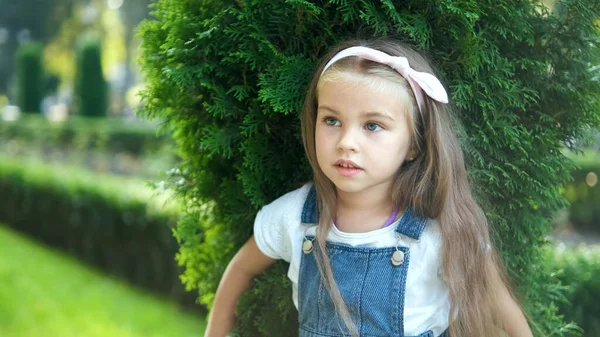Portret ślicznej dziewczynki stojącej na zewnątrz w zielonym letnim parku — Zdjęcie stockowe