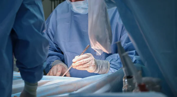 Equipe de médicos profissionais que operam um paciente realizando cirurgia de corte aberto na sala cirúrgica. Conceito de cuidados de saúde e intervenção médica — Fotografia de Stock