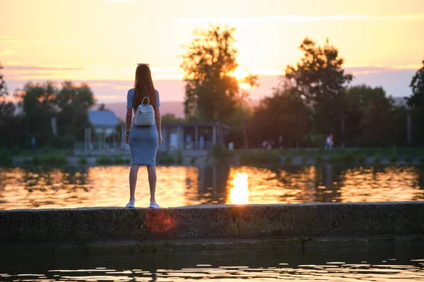 Молодая женщина в повседневной одежде отдыхает на берегу озера теплым вечером. Летние каникулы и концепция путешествия — стоковое фото