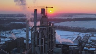 Gün batımında endüstriyel üretim alanında yüksek beton yapılı çimento fabrikası kulesinin havadan görüntüsü. Üretim ve küresel sanayi kavramı