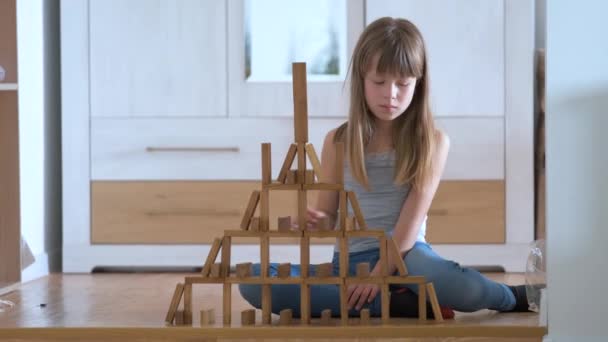 Glad barn flicka spelar spel stapling trä leksaksblock i hög lugg struktur. Handrörelsekontroll och uppbyggnad av beräkningsfärdigheter — Stockvideo