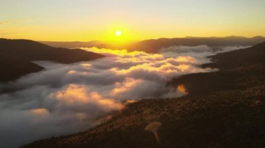 Sonbahar gündoğumunda karanlık dağ ormanları üzerinde parlak sisli bir sabah manzarası. Şafak vakti vahşi ormanın güzel manzarası