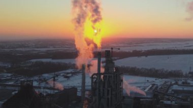 Gün batımında endüstriyel üretim alanında yüksek beton yapılı çimento fabrikası kulesinin havadan görüntüsü. Üretim ve küresel sanayi kavramı