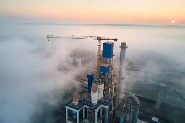 Vista aérea de la fábrica de cemento con estructura de planta de hormigón alto y grúa torre en el sitio de fabricación industrial en la noche brumosa. Producción y concepto de industria global — Foto de Stock