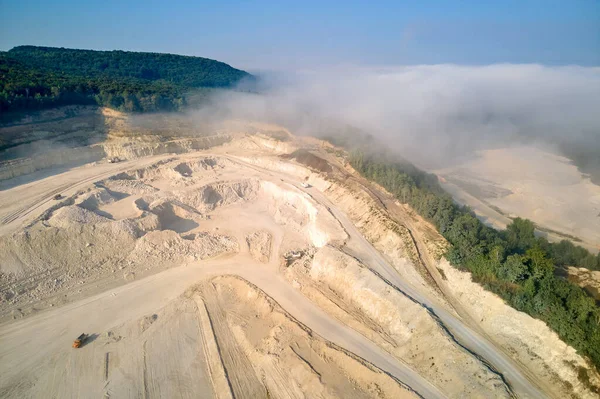 Kazı araçları ve çöp kamyonları ile inşaat endüstrisi için kireçtaşı malzemelerinin açık çukur madenciliğinin hava görüntüsü
