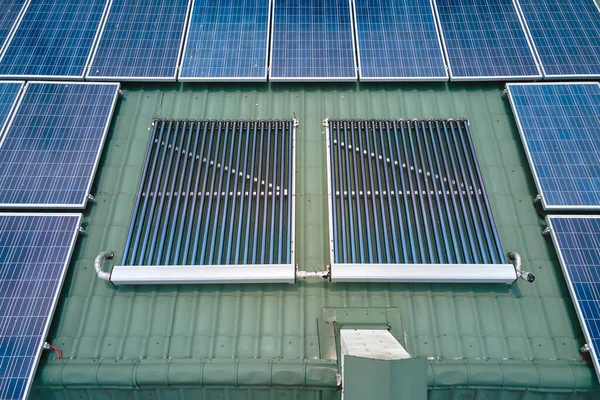 Costruzione tetto con file di pannelli fotovoltaici blu e collettori solari ad aria sottovuoto per il riscaldamento dell'acqua e la produzione di energia elettrica ecologica pulita. Energia elettrica e termica rinnovabile a emissioni zero — Foto Stock