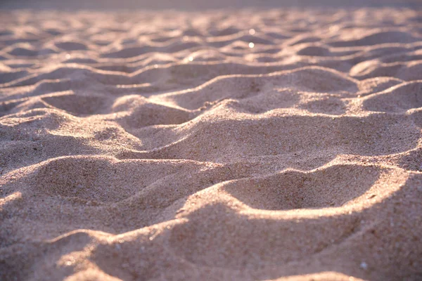 Крупним планом чиста жовта поверхня піску, що покриває приморський пляж, освітлений вечірнім світлом. Концепція подорожей та відпусток — стокове фото
