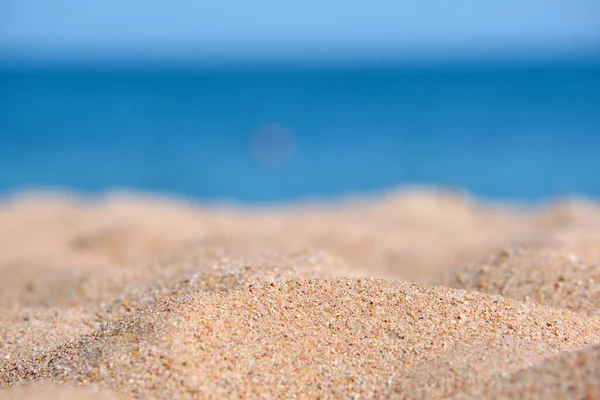 Close up de superfície de areia amarela limpa cobrindo praia à beira-mar com água do mar azul no fundo. Conceito de viagem e férias — Fotografia de Stock