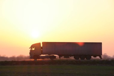 Kargo karavanı olan yarı kamyon akşam vakti otobanda mal taşır. Teslimat ulaşım ve lojistik kavramı
