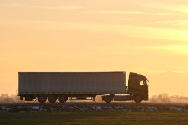 Kargo karavanı olan yarı kamyon akşam vakti otobanda mal taşır. Teslimat ulaşım ve lojistik kavramı