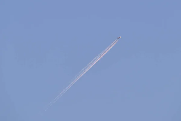 Aereo a reazione passeggeri distanti che volano in alta quota su cielo blu chiaro lasciando tracce di fumo bianco di contrail dietro. Concetto trasporto aereo — Foto Stock