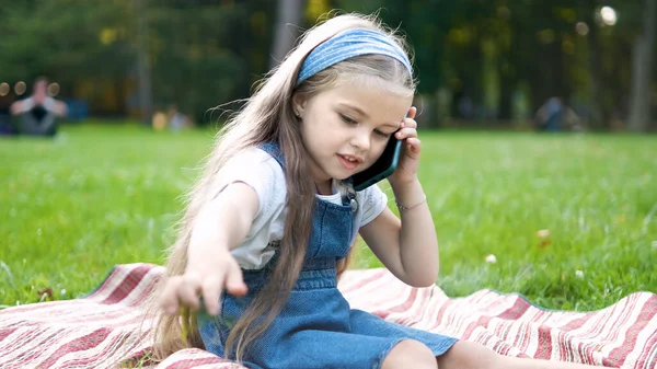 여름 공원에서 셀 폰으로 대화를 나누고 있는 행복 한 어린 소녀 — 스톡 사진