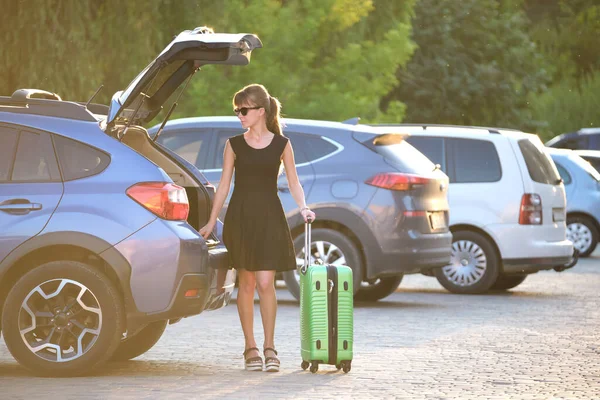 Joven conductora cargando la maleta de equipaje dentro de su coche. Concepto de viajes y vacaciones — Foto de Stock