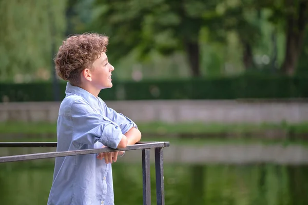 Молодий щасливий хлопчик розслабляється в літньому парку. Позитивна дитина насолоджується літнім часом на відкритому повітрі. Концепція добробуту дітей — стокове фото