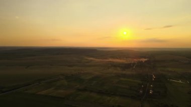 Yeşil ekili tarlaların, büyüyen ekinlerin ve parlak yaz akşamlarında uzak köy evlerinin hava manzarası.