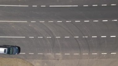 Beyaz işaretli ve hızlı sürüş arabalı şehir caddesinin havadan görünüşü. Şehir trafiğinin insansız hava aracının üst görüntüsü