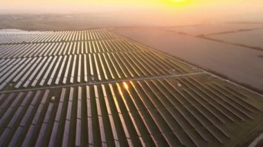 Akşamları temiz elektrik enerjisi üretmek için sıra sıra güneş fotovoltaik panelleri olan sürdürülebilir büyük elektrik santralinin havadan görünüşü. Sıfır emisyonlu yenilenebilir elektrik kavramı