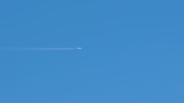 Aereo a reazione passeggeri distanti che volano in alta quota su cielo blu chiaro lasciando tracce di fumo bianco di contrail dietro. Concetto trasporto aereo — Video Stock