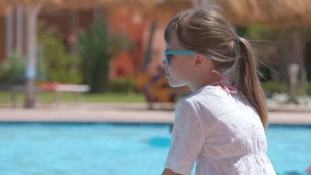 Menina feliz em vestido branco relaxante no lado da piscina no dia ensolarado de verão — Vídeo de Stock