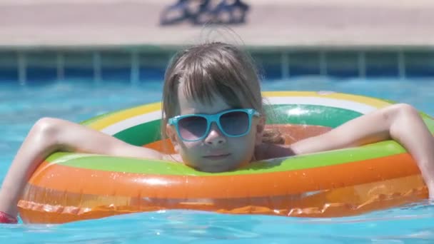 Happy baby girl pływanie na nadmuchiwanym okręgu w basenie w słoneczny letni dzień podczas tropikalnych wakacji — Wideo stockowe
