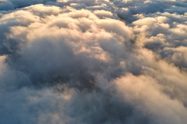 Yükseklerden gökyüzü manzarası. Akşamları yoğun, kabarık kümülüs bulutları uçuşuyor. Uçak penceresinden gün batımı inanılmaz.