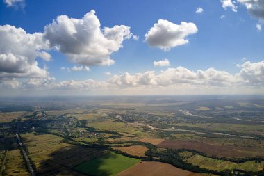 Güneşli bir günde, yeryüzünün yüksek irtifasından beyaz kabarık kümülüs bulutlarıyla kaplı hava manzarası.