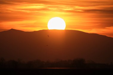 Güzel bir akşam panoramik manzarası. Gün batımında güneş batarken uzak dağ tepeleri ve asfalt yolda batıyor.