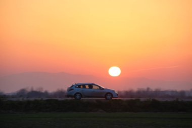 Gün batımında şehir içi yolda hızlı giden bir araba. Akşamları otoyol trafiği