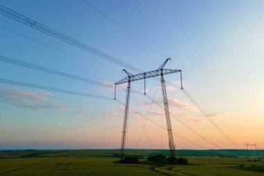 Gün batımında elektrik hatları olan yüksek voltaj kuleleri.