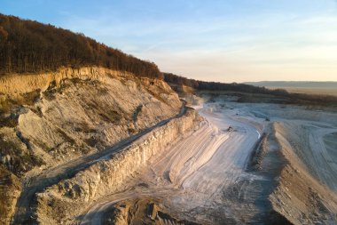 Kazı makineleri ve çöp kamyonlarıyla inşaat endüstrisi için kumtaşı malzemelerinden oluşan açık maden manzarası. Madencilik ve kullanışlı mineral üretiminde ağır ekipman