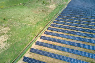Yeşil alandaki güneş enerjisi santralinin havadan görüntüsü. Temiz ekolojik enerji üretmek için panelleri olan elektrik çiftliği