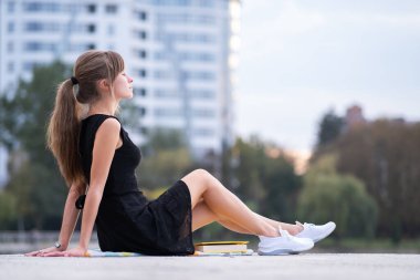 Şehir caddesinde yalnız başına oturan yalnız kadın sıcak yaz gününün tadını çıkarıyor. İyi olmak ve temiz hava kavramında rahatlamak.