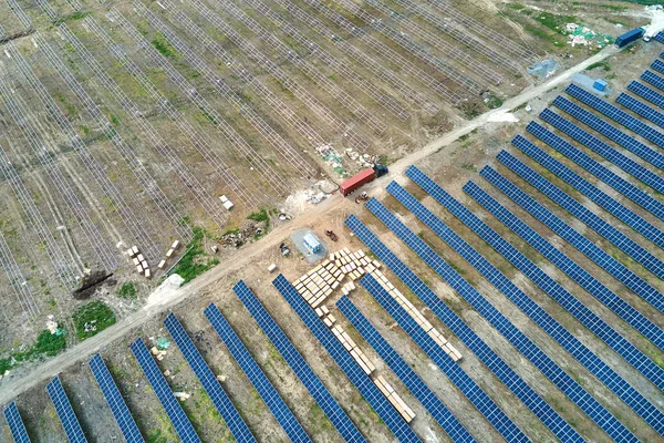 Vue aérienne de la centrale électrique en construction avec camion livrant des pièces d'assemblage pour panneaux solaires sur châssis métallique pour la production d'énergie électrique. Développement de l'électricité renouvelable — Photo