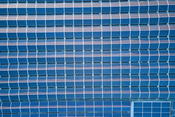 緑の生態系電力を生産するための産業用建物の屋根の上に青い太陽光パネルを搭載した太陽光発電所の空中ビュー。持続可能なエネルギー概念の生産 — ストック写真