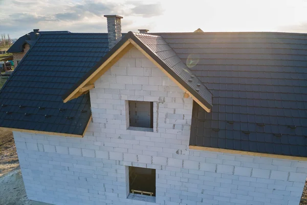 Vista aérea de casa inacabada con paredes de hormigón ligero aireado y marco de techo de madera cubierto con azulejos metálicos en construcción — Foto de Stock