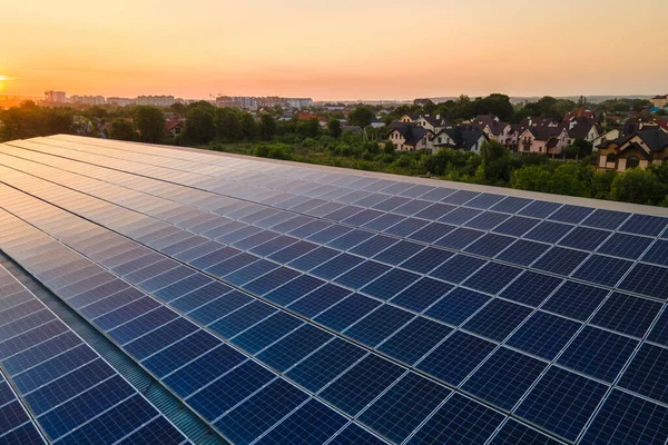 stock image Blue photovoltaic solar panels mounted on building roof for producing clean ecological electricity at sunset. Production of renewable energy concept