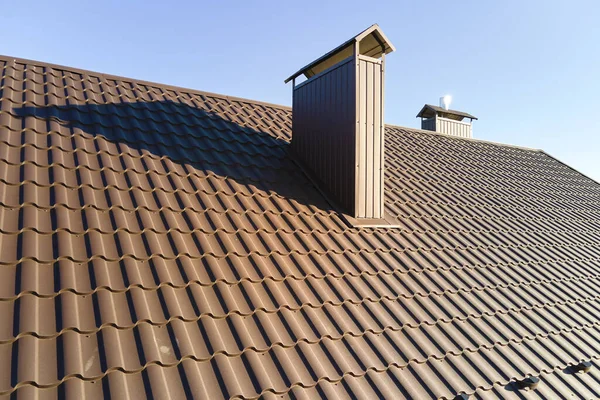 Chimney on house roof top covered with metallic shingles under construction. Tiled covering of building. Real estate development — Stockfoto