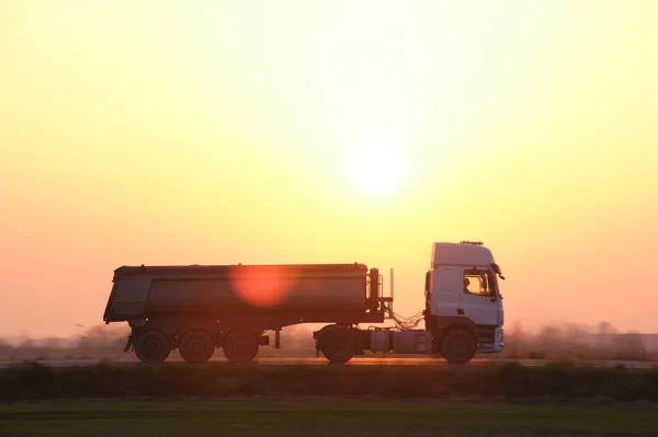 Semi-vrachtwagen met kipwagen die 's avonds zand vervoert uit steengroeve en over de snelweg vervoert. Levering transport en logistiek concept — Stockfoto
