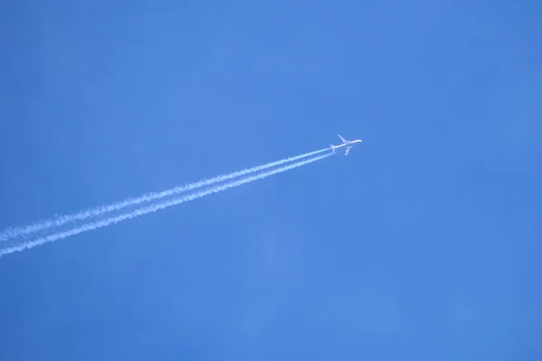 Distant passenger jet plane flying on high altitude on clear blue sky leaving white smoke trace of contrail behind. Air transportation concept — Stock Photo, Image