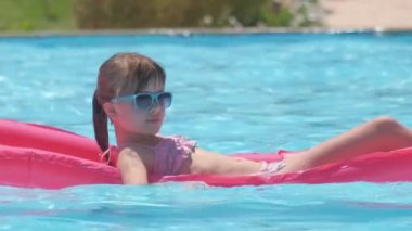Mutlu çocuk tropik tatillerde güneşli bir yaz gününde havuzda şişme şişme yatakta dinleniyor. Yaz etkinlikleri konsepti