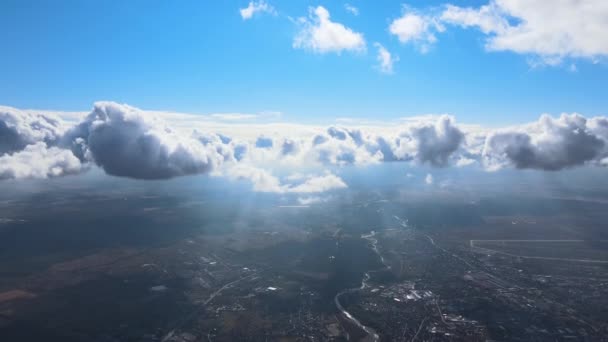 Widok z okna samolotu na dużej wysokości odległego miasta pokrytego białymi chmurami kumulującymi — Wideo stockowe