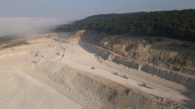 Kazı araçları ve çöp kamyonları ile inşaat endüstrisi için kireçtaşı malzemelerinin açık çukur madenciliğinin hava görüntüsü