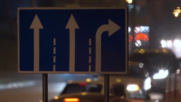 Direction panneaux routiers avec des voitures floues sur la circulation de la ville la nuit. Concept de transport urbain — Video